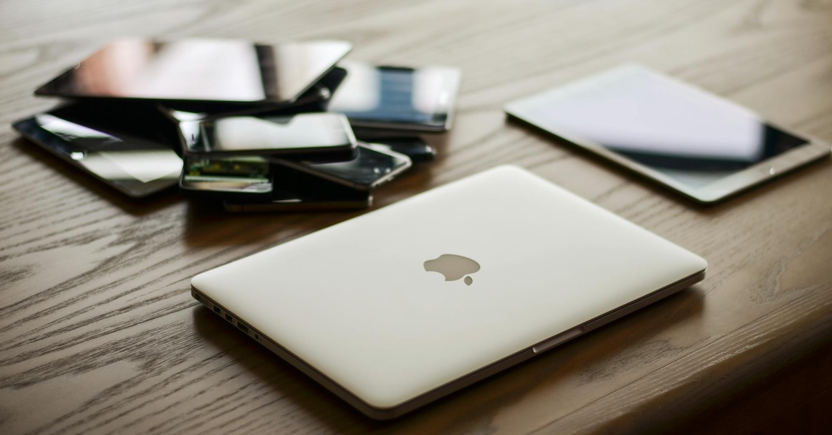 a sexy photo of a Macbook with some other devices as well, tablet and phones